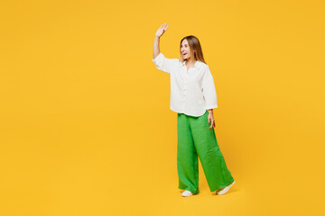 Fototapeta na wymiar Full body side view young caucasian happy woman she wearing white shirt casual clothes walk go strolling waving hand look aside isolated on plain yellow background studio portrait. Lifestyle concept.