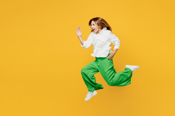 Fototapeta na wymiar Full body side profile view young excited caucasian happy woman she wears white shirt casual clothes jump high run fast hurry up isolated on plain yellow background studio portrait. Lifestyle concept.