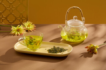Transparent teapot and teacup filled with warm tea arranged on brown plate. Asian tea set. Hot tea...