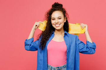 Young woman of African American ethnicity wear blue shirt casual clothes hold yellow skatebaord pennyboard look camera look camera isolated on plain pastel pink background studio. Lifestyle concept.