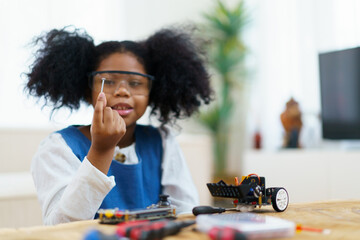 Happy cheerful American - African black ethnicity female university student learning about robotic and programing by herself, woman assemble a robot.