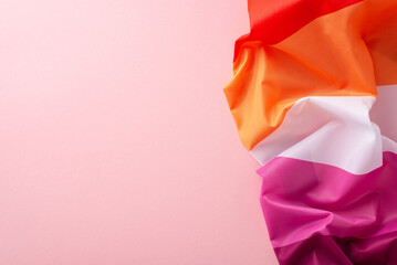 Capture the essence of International Lesbian Day with a top view photo featuring the Lesbian Pride flag, symbolizing female unity on a gentle pink base with empty space