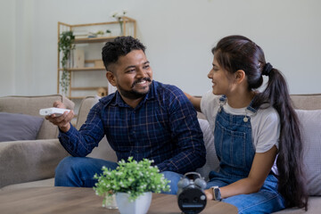 Young couple watching tv television together while relaxing on sofa at home