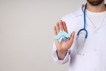 A blue ribbon with a mustache in a male doctor's hand