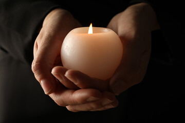 Mourning candles in hands, on a dark background.