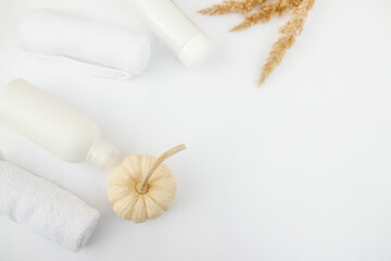 Plastic container for shampoo without etiket and pumpkin with towels on a white background. Cosmetics bottle mockup with autumn leaves.