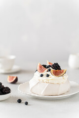 Homemade delicious meringue Pavlova cake with fresh blueberry, figs, blackberry and mascarpone on a white background. Vertical. Copy space. Confectionery, recipe, menu. Meringue summer dessert
