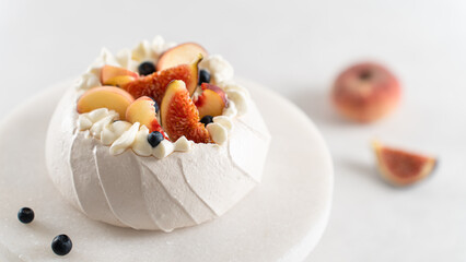 Homemade delicious meringue Pavlova cake with fresh blueberry, figs, peach and whipped cream on a white background. Close up. Confectionery, recipe, menu. Yummy meringue summer dessert