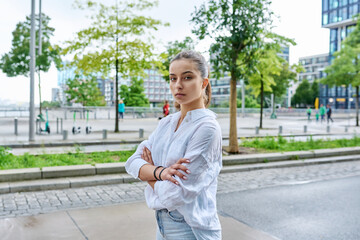 Portrait of teenage girl with crossed arms on street of city
