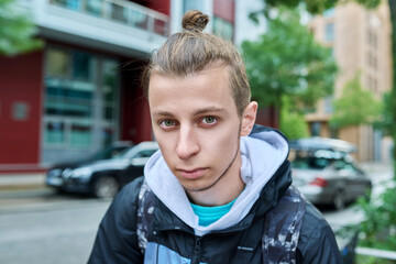 Fototapeta na wymiar Portrait of handsome guy 19, 20 years old, city street background