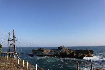 Fototapeta na wymiar a bridge over the sea connecting shore and rocky cliff 