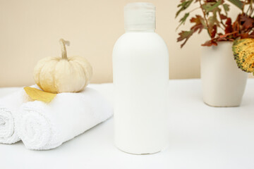 Blank plastic cosmetics on the background of autumn leaves and pumpkin. Autumn cosmetics for hair and body. mockup,