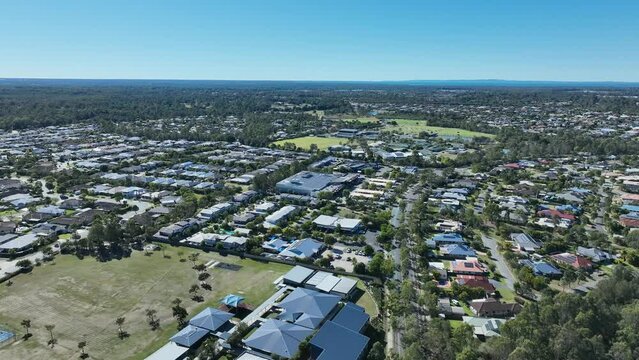 Drone pull away tracking shot of Narangba Brisbane Queensland Suburb. Narangba Valley State High School and town in shot. Clear mid day shot.