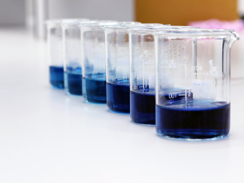 The beakers with blue color range solution on bench laboratory, with reactive blue color solvent for analysis absorbent experiment in waste water treatment. bright light effect using for clean room.