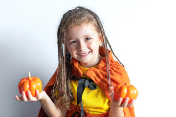 happy little girl with pigtails dreadlocks with pumpkin in witch costume, laughing, smiling, scaring and saying boo. Child for fun scary halloween holiday