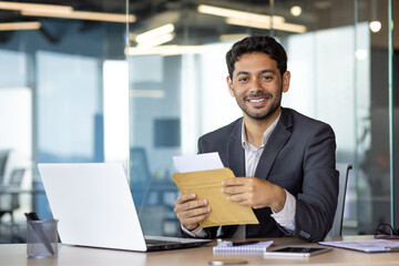 Portrait of young successful businessman at workplace, man received mail envelope notification...