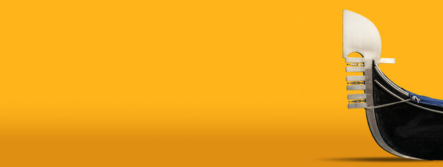 Close-up of a Gondola prow on a yellow and orange background with copy space. Typical Venetian rowboat, Veneto, Italy, Europe. © Alberto Masnovo