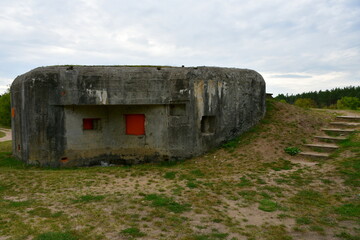 A close up on a bunker or bomb shelter made out of concrete standing next to a bridge and a vast...