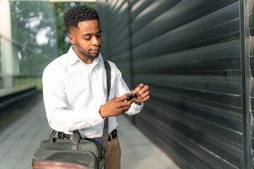 A young African-American man, ready to head home after work, puts his headphones on, immersing...