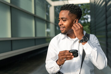 A young African-American man, ready to head home after work, puts his headphones on, immersing...