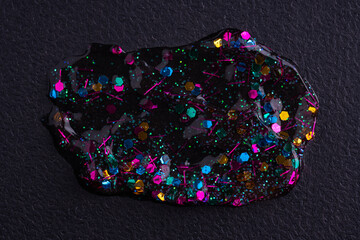 Colorful glitter sparkle confetti background liquid drops on black canvas. Sample of glitter paint on black paper background.