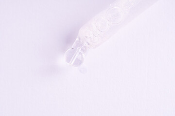 Serum gel in the pipette on white background. Cosmetic liquid dropper with bubbles, top view.