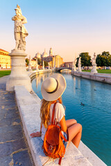 Young woman travel in Italy- Padua, Padova city, river and bridge- Prato della Valle square and...