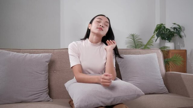 Unhappy young woman touching forehead, yearning, thinking about relationship problems, feeling depressed and lonely, sitting on couch alone, frustrated female suffering from headache or migraine