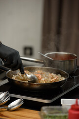 preparation of traditional spanish tapas served on plates on black table background. Patatas Bravas with Gambas Ajillo