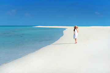 Happy young Asian girl walking on white sand beach with clear blue sea and sky. Teenager girl...