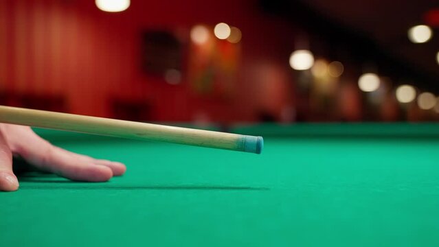 A young man plays American billiards. Russian billiards, an American in a billiards club and bar. Dark colors in the billiard club. A man pockets snooker balls.