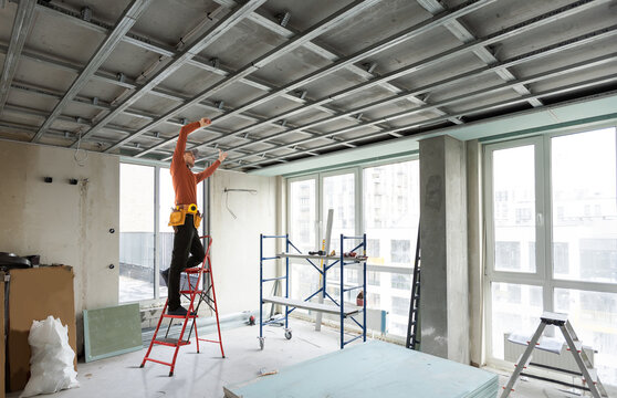 Worker stands on a ladder and make a ceiling