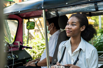 Black woman traveller standing with tuktuk locar taxi during summer vacation in Chiangmai, Thailand 