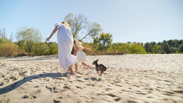 Mom and daughter in white dresses running on the beach and laughing