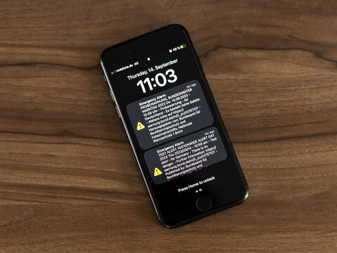 DRESDEN, GERMANY - 14. September 2023: Test alert notification on a smartphone during the nationwide alert day in Germany. Notifications in German and English language on a black screen.