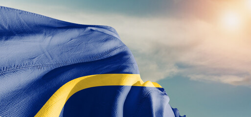 Nauru national flag cloth fabric waving on beautiful sky Background.
