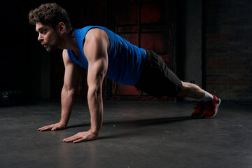 Fototapeta na wymiar full length of strong man in sportswear training in plank pose in darkness of night street