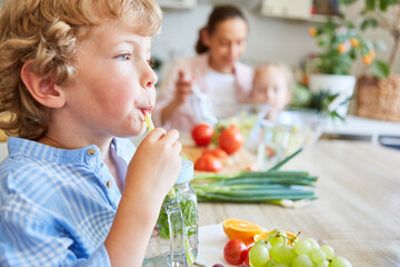 Cute boy sipping detox water in kitchen