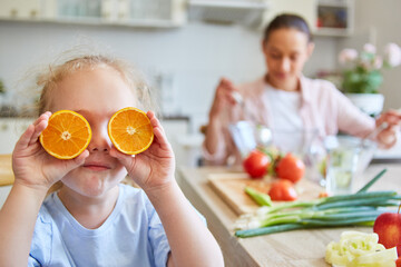 Girl holding slices of oranges in front of eyes