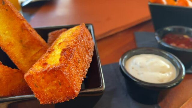 Hot deep fried polenta chips sticks and cheese sticks with sauces, traditional tapas in a restaurant, 4K shot