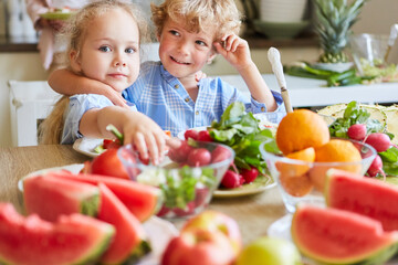 Cute siblings making vegetable salad at home