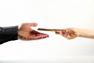 Bribery. A female's hand gives a bribe a man's hand in a shirt. Side view. White background. Close up. Concept of world anti-corruption day, December 9.