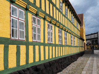 Yellow and green half-timbered building with row of windows