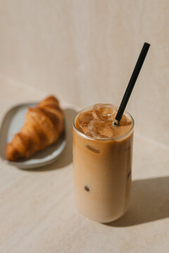 Close-up of a glass of iced coffee and a croissant on a table