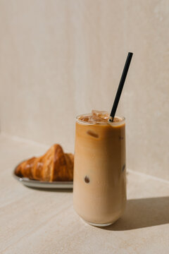 Close-up of a glass of iced coffee and a croissant on a table
