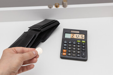 Coins in a post and next to it a calculator with the word zusame. The concept of pension contributions for the future and old age. The concept of raising premiums for entrepreneurs