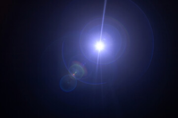 Glare on a black background. A camera pointed at the light produces a special flare effect. A ray...