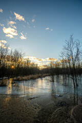Mystical frozen lake at sunset. Sand and dried old trees