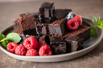 Chocolate cake and fresh raspberries on a rustic plate. Brownie cake.