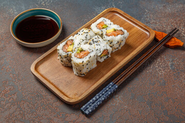 California rolls au saumon sur une ardoise avec une sauje soja et baguettes. Cusine japonaise.